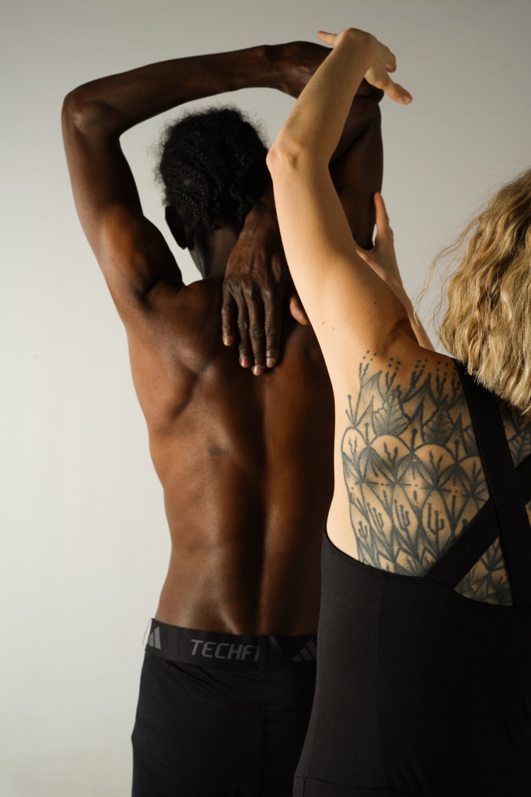 Yogalehrerin von hinten, die einen Schüler anleitet